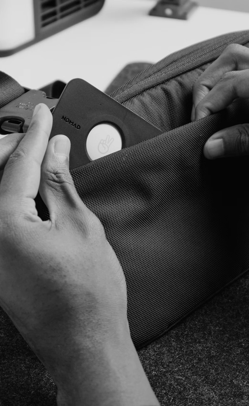 Hands slipping a tracking tag into the pocket of a bag